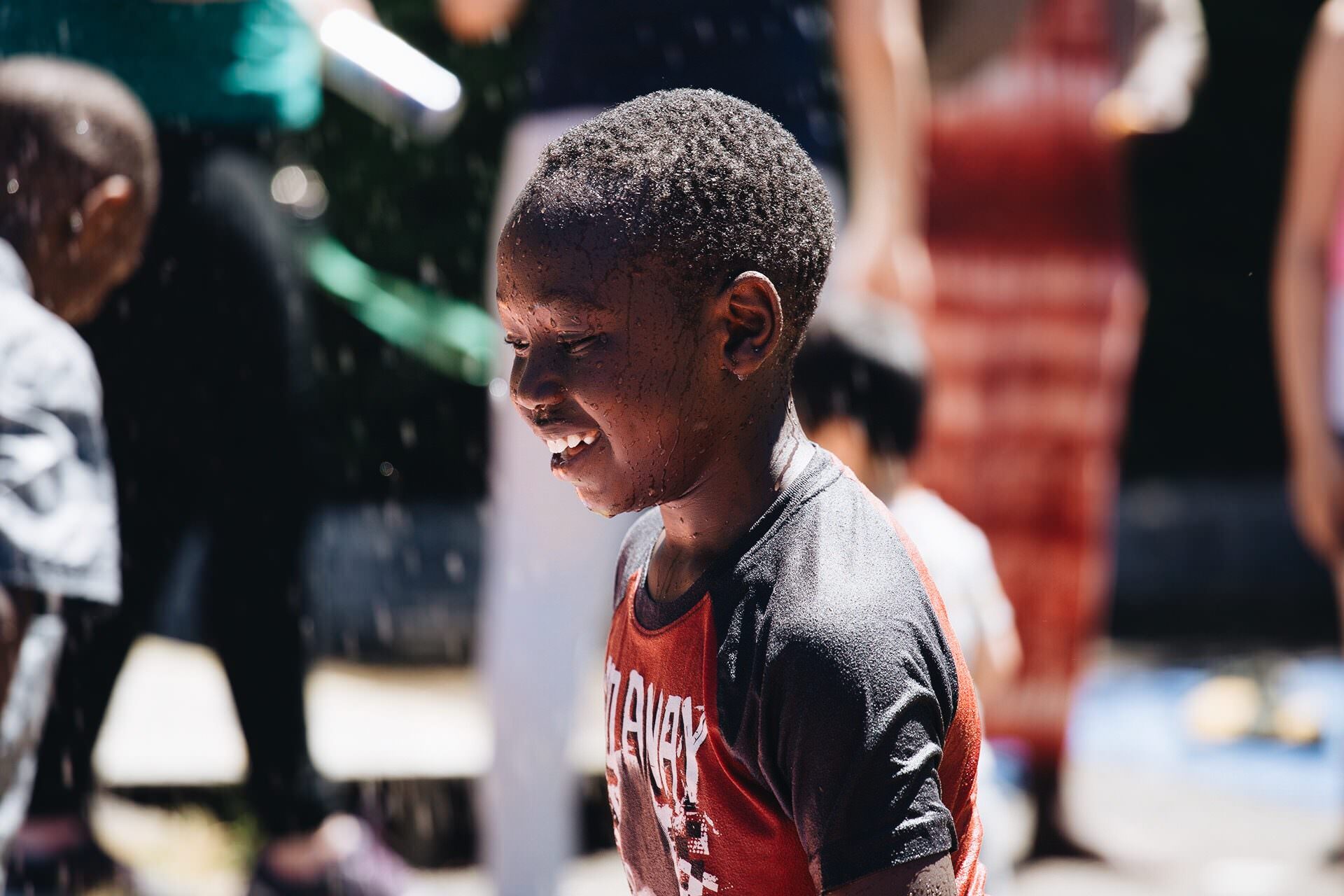 Boy smiling in sprinkler