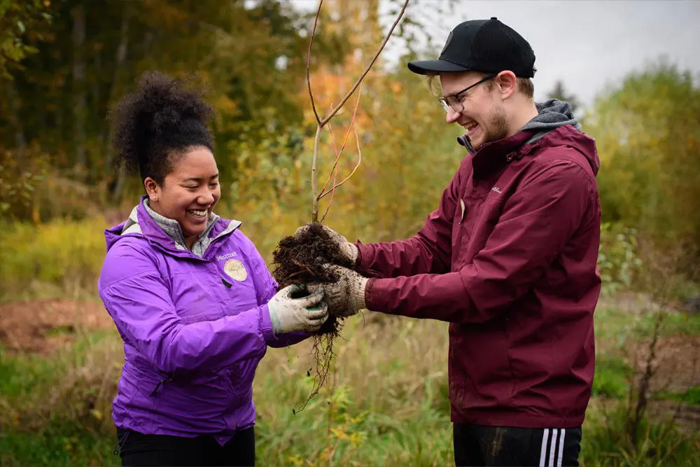 Smiling people holding a plant