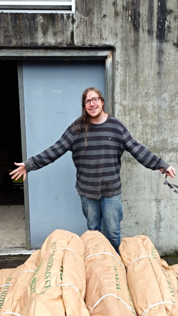 Forterra's Project Manager Daniel Hachet stands over a stack of the delivered trees and smiles at the camera